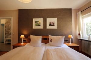 Blick über das Doppelbett der Ferienwohnung Lindenblüte mit dekorativer Rückwand hinterm Bett