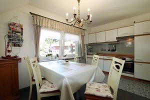 Küche mit Esstisch und weißen Stühlen der Ferienwohnung Lindenblüte