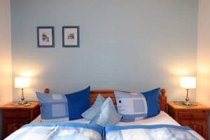 Doppelbett der Blauen Stube mit blauer Bettwäsche und blauer Rückwand hinterm Bett